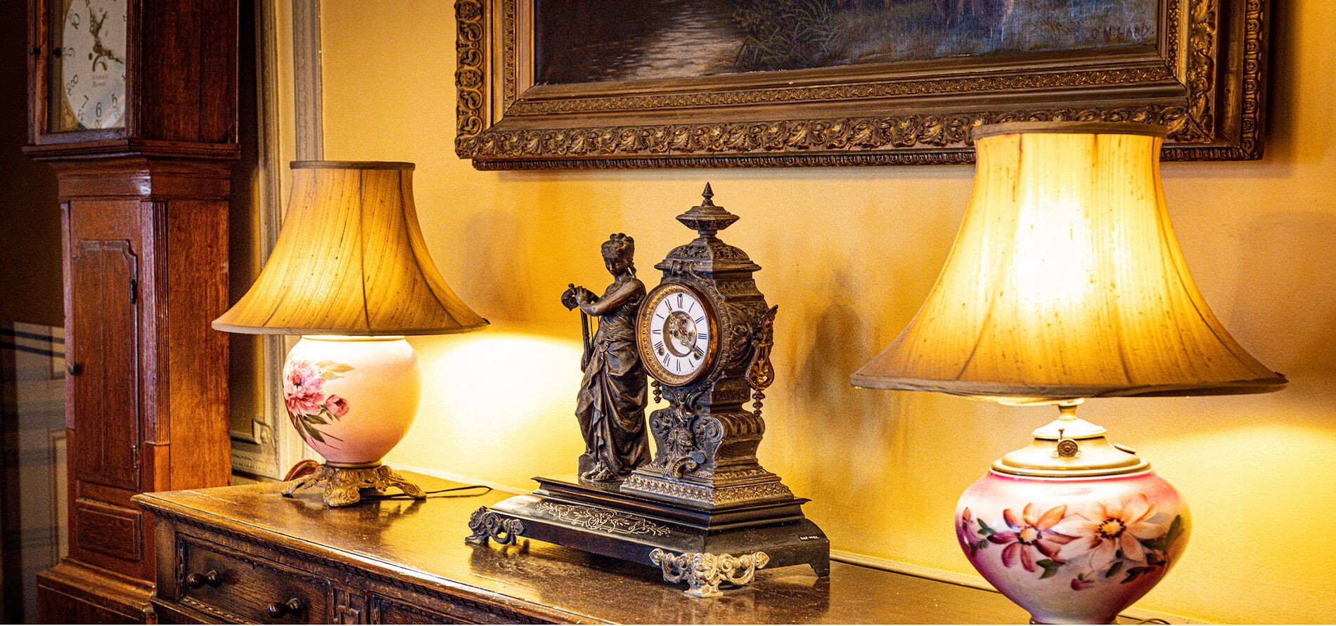 Pendola in bronzo e lampade in porcellana d'epoca su un cassettone antico